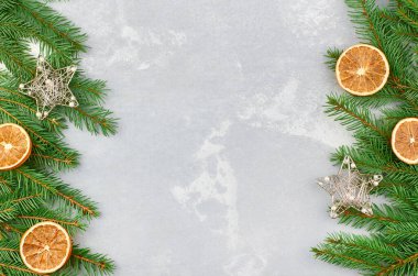 Köknar ağacı dalları ve gri beton arka planda kuru portakallarla Noel çerçevesi. Üst görünüm, düz görünüm, kopyalama alanı.