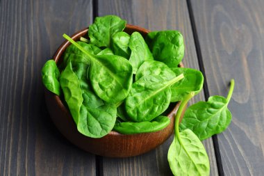 Ispanak yaprakları ahşap kasede, arka planda. Vegan gıda yaşam tarzı konsepti.