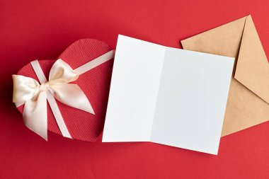 Sevgililer Günü kartı modeli. Zarf ve kalp hediye kutusuyla kırmızı kağıt arka plan, üst görünüm, boşluk kopyala