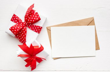 Tebrik kartı modeli ve hediye kutuları beyaz ahşap zemin üzerinde kırmızı kurdele, üst görünüm, boşluk kopyala