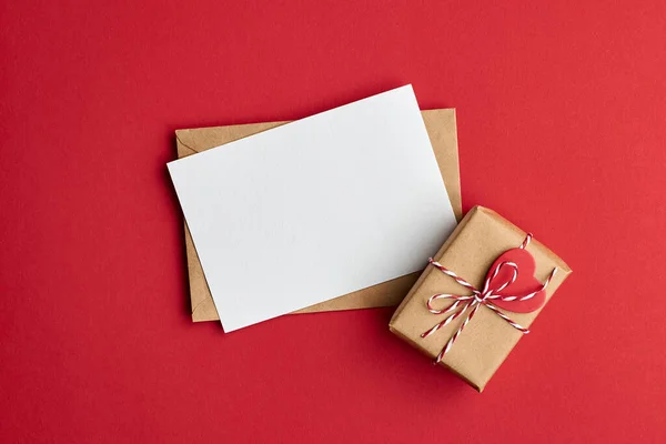 情人节贺卡 内装信封和礼品盒 红纸背景 顶视图 复制空间 — 图库照片
