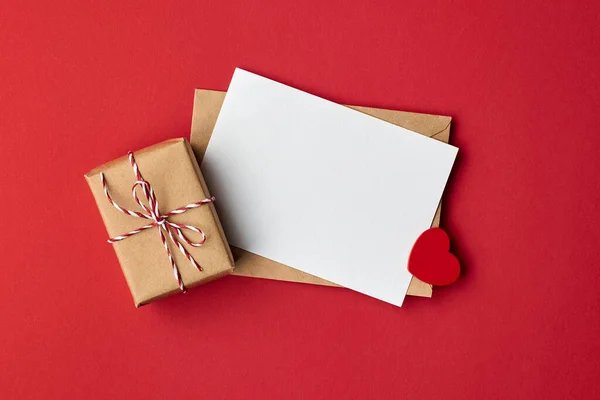 Walentynki karta makieta z koperty i pudełko z sercem na czerwonym tle papieru — Zdjęcie stockowe