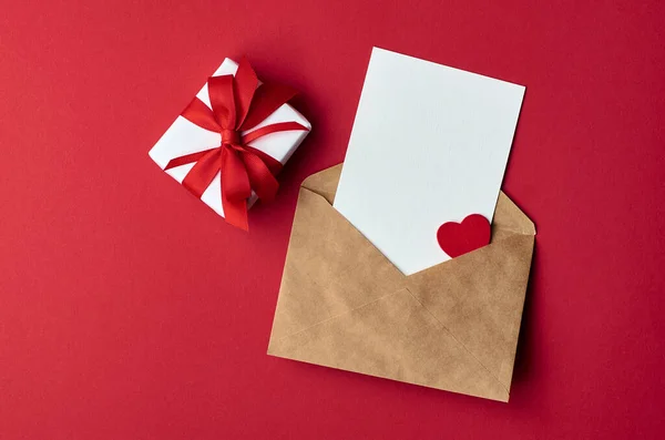 Tarjeta de San Valentín maqueta con sobre y caja de regalo con corazón sobre papel rojo — Foto de Stock