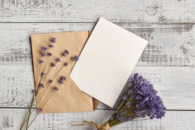 Zarflı tebrik kartı modeli ve eski ahşap arka planda kuru lavanta çiçekleri.