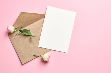 Zarflı tebrik kartı modeli ve pembe arka planda taze güller.