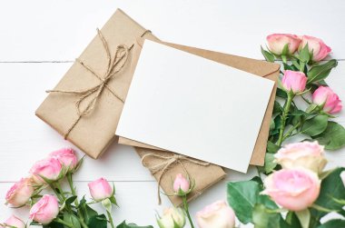 Tebrik kartı modeli. Taze güller ve beyaz ahşap arka planda hediye kutuları.