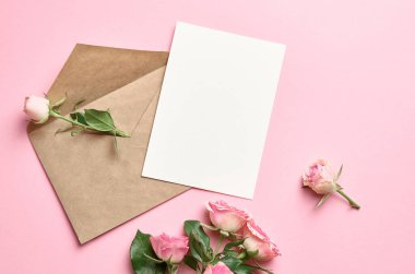Zarflı tebrik kartı modeli ve pembe arka planda taze güller.