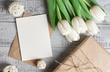 Hediye kutulu boş tebrik kartı, lale çiçekleri buketi ve tahta arka planda kopyalama alanı, üst görünüm