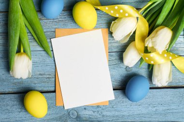 Paskalya bayramı tebrik kartı. Lale çiçekleri ve ahşap arka planda renkli yumurtalar.