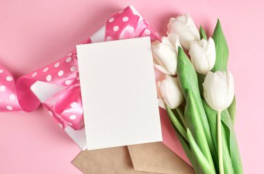 Hediye kutulu boş tebrik kartı ve pembe kağıtta lale çiçeği buketi, üst görünüm, boşluk kopyala