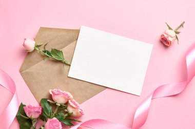 Zarflı tebrik kartı modeli, pembe kurdele ve kağıt arkaplanda taze güller, kopya alanı olan kart