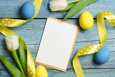 Paskalya bayramı tebrik kartı. Üzerinde lale çiçekleri ve ahşap arka planda renkli yumurtalar var.