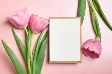 Zarflı tebrik kartı modeli ve pembe arka planda lale çiçekleri, üst görünüm, boşluk kopyala