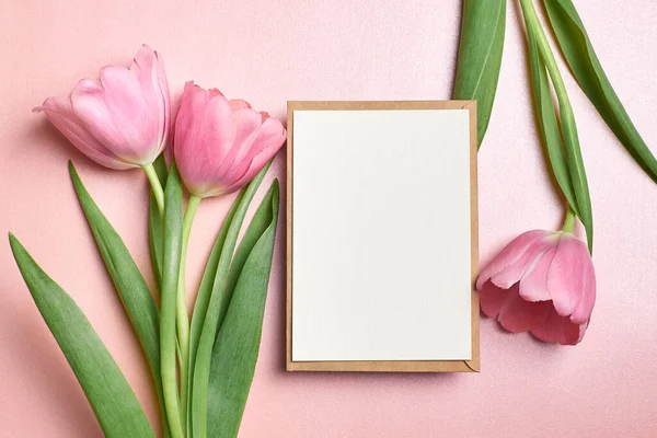 Zarflı tebrik kartı modeli ve pembe arka planda lale çiçekleri, üst görünüm, boşluk kopyala