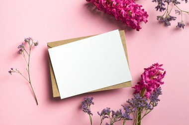 Pembe kağıt arka planda limonyum ve sümbül çiçekli tebrik ya da davet kartı modeli, üst görünüm, kopyalama alanı