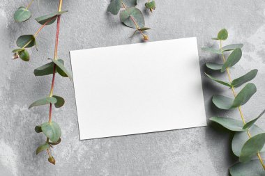 Gri taşlı arka plan üzerinde okaliptüs dalları olan davetiye kartı modeli, üst görünüm, boşluğu kopyala