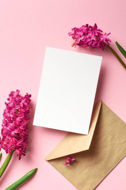 Davetiye ya da tebrik kartı modeli. Zarf ve bahar çiçekleri. Pembe kağıt arka plan, üst görünüm, kopyalama alanı.