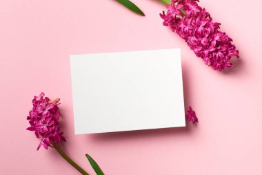 Pembe kağıt arkaplan, üst görünüm, kopyalama alanı üzerinde bahar sümbülü çiçekleri olan tebrik ya da davet kartı modeli