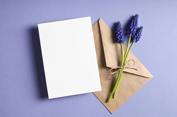 グリーティングカード固定モックアップ付き封筒と春青ムスカリの花 トップビュー コピースペース — ストック写真
