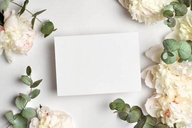 Davetiye ya da tebrik kartı kopyaları ve okaliptüs dallı beyaz şakayık çiçekleri.