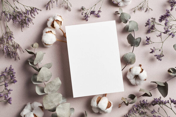 Invitation or greeting card mockup with eucalyptus twigs and cotton plant flowers decorations, copy space