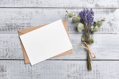 Ahşap zemin üzerinde lavanta ve okaliptüs kuru buket ile selamlama veya davet kartı modeli, üst görünüm, kopyalama alanı
