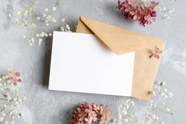 Davetiye ya da tebrik kartı modeli. Zarf ve kuru çiçek süslemeleri. Gri arkaplanda boş kart modeli.
