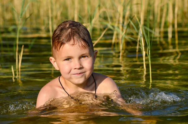 Jongen zwemt in het meerwater met een groene tint. — Stockfoto