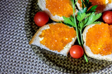 Kırmızı havyarlı sandviç, maydanoz ve domatesli cam tabakta. Kutlama konsepti.
