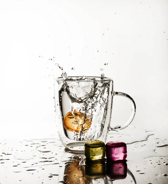 Ice cubes splashing into a drink glass isolated on white.