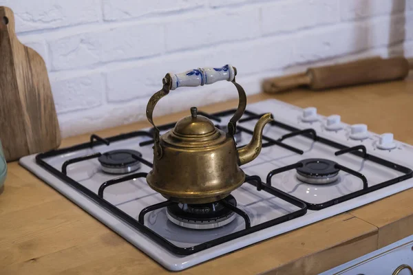 On the gas stove is a copper kettle with a beautiful handle.