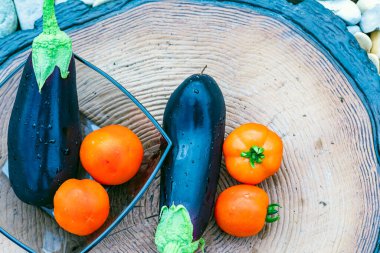 Taze patlıcan ve ağaç kütüğünde su damlası olan domatesler..