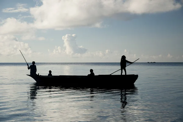 Silhouette of sea gypsy family in canoe.