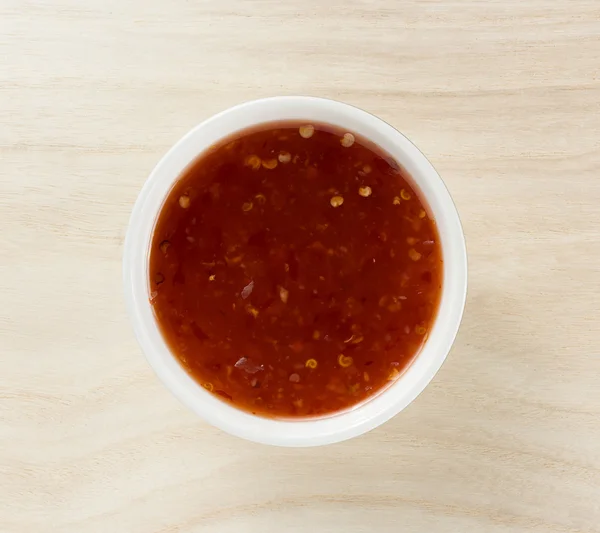 Miska z sosem chili na tle drewna — Zdjęcie stockowe