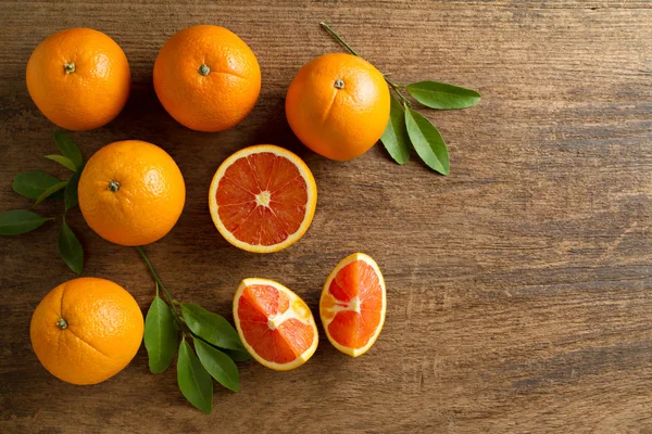 Naranjas frescas con rodajas y hojas sobre fondo de madera . Fotos De Stock