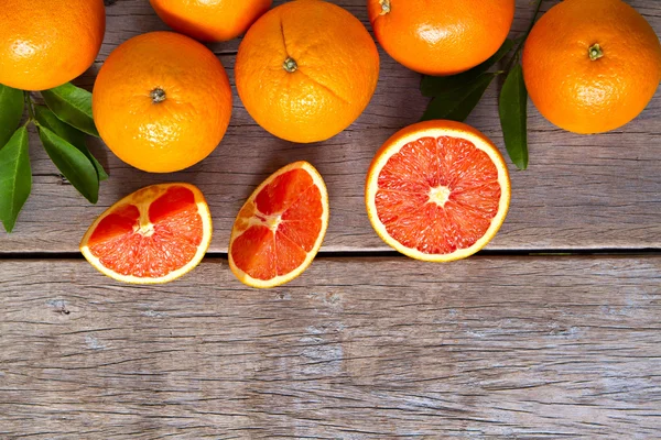 Naranjas frescas con rodajas y hojas sobre fondo de madera . Imágenes De Stock Sin Royalties Gratis