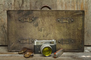 Bavul, kamera, güneş gözlüğü, ağız organ, şal ve ahşap arka plan pasaportla seyahat retro kavramı oluşur