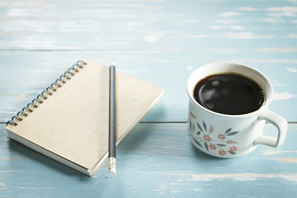 A cup of coffee and notebook on wooden background. — Stock Photo, Image