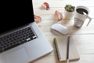 Bir fincan kahve, dizüstü bilgisayar, fare, defter, kalem ve ca