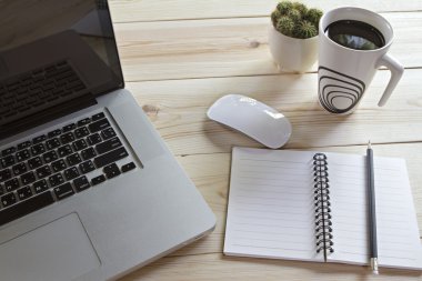 Bir fincan kahve, dizüstü bilgisayar, fare, defter, kalem ve ca