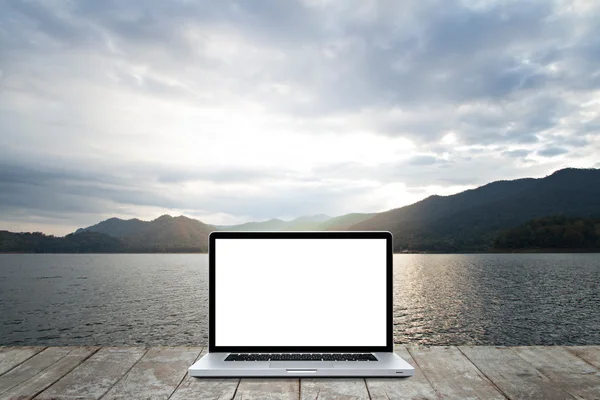 Laptop-datamaskin på tre med morgenmiljø ved innsjøen og – stockfoto