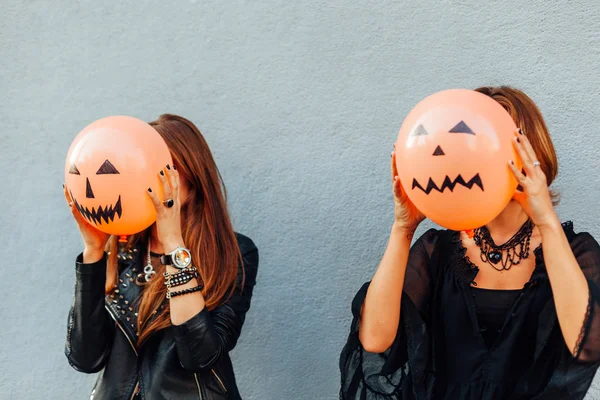 Girls hiding behind Halloween balloons