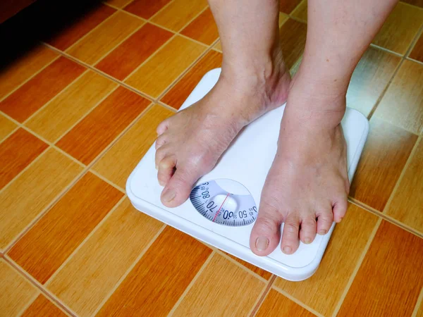 Foot of aged woman standing on weight scale
