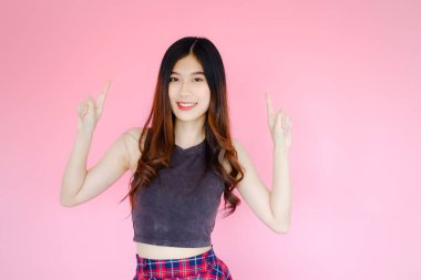 Portre güzel Asyalı neşeli kız elini doğru tarafa uzattı ürününü veya mesajını gösterdi ve pembe arka planda ışıldayan gülümseme, duygu hareketi, mutlu yaz hayatı konsepti