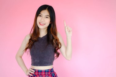 Portre güzel Asyalı neşeli kız elini doğru tarafa uzattı ürününü veya mesajını gösterdi ve pembe arka planda ışıldayan gülümseme, duygu hareketi, mutlu yaz hayatı konsepti