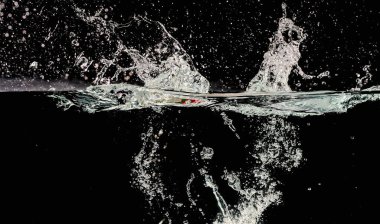 Su sıçrıyor ve kabarcıklar siyah arkaplanda dalgalanıyor