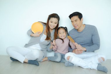 Mutlu Asyalı aile ve kızı birlikte yemek ve oyuncak oynuyorlar.