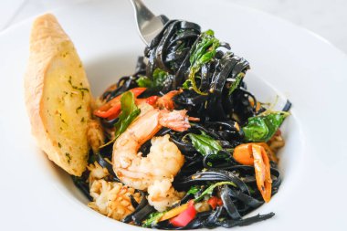 Deniz ürünleri, biber, sarımsak ve kutsal fesleğen yapraklı siyah mürekkep linguini.