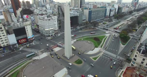 Aerial Drone scen av obelisken i Buenos Aires, Argentina, vid soluppgången på morgonen. 9 de Julio main Avenue, 9 juli. Trafik och människor går för att arbeta. Kameran går långsamt ner och panorering upp. — Stockvideo