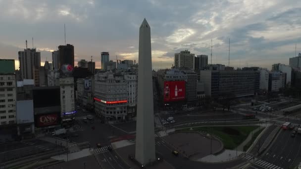 Aerial Drone scene of Obelisk in Buenos Aires, Argentina, at sunrise in the morning. 9 de Julio main Avenue, 9 of july. Traffic and people going to work. Camera moving back getting into the city. — Stock Video